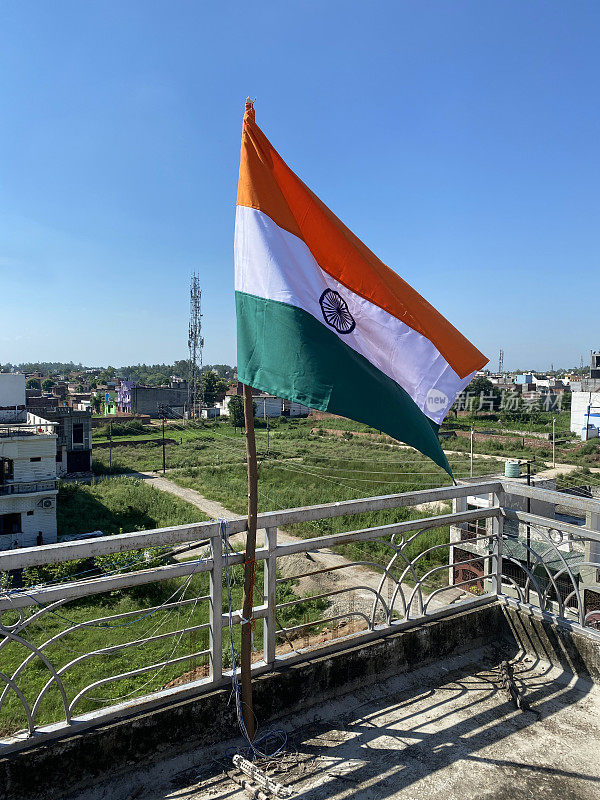 印度国旗(三色)从木制旗杆上飘扬，庆祝独立日，卡迪布国旗的藏红花(橙色)，白色和绿色条纹与中央藏青色Ashoka Chakra，重点在前景